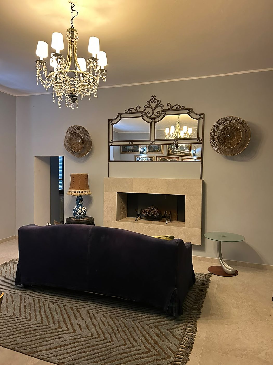 De woonkamer met een donkerblauwe bank voor de beige open haard