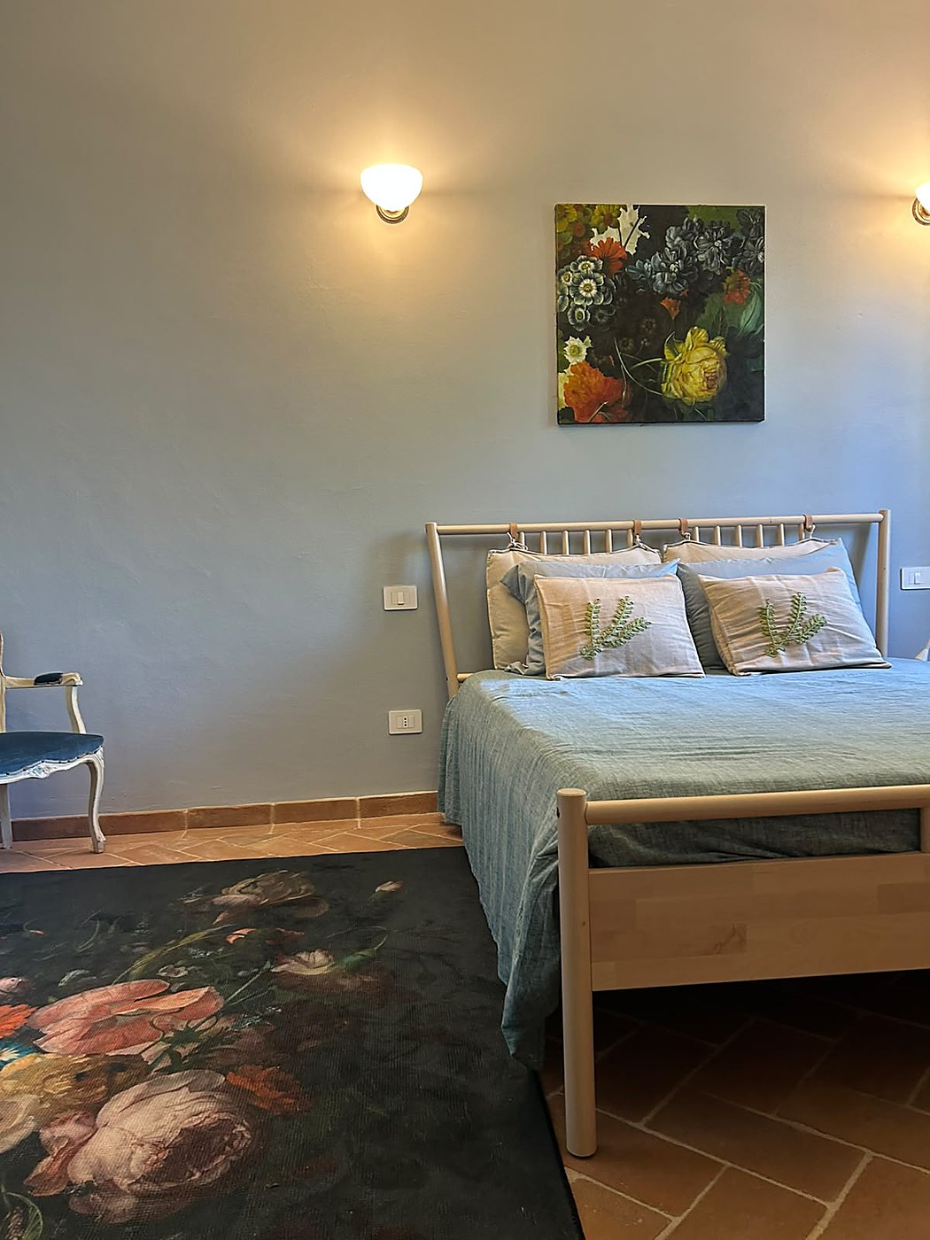 De slaapkamer met een houten bed, lichtblauw bedsprei en sfeervolle wandlampen